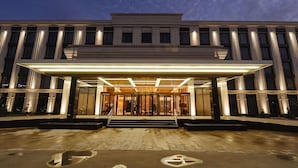 L’entrée d’un hôtel moderne, avec une façade en verre, un escalier central et un espace d’entrée abrité.