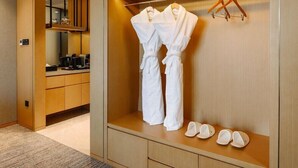 Une chambre d’hôtel dotée d  ’un dressing où se trouvent un peignoir et des chaussons.