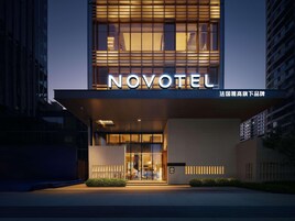 Una entrada de hotel moderna con un llamativo letrero 'NOVOTEL', puertas de vidrio y una fachada bien iluminada.