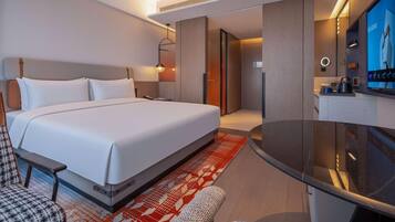 A hotel room with a bed, a desk, a chair, a television, and a bathroom.