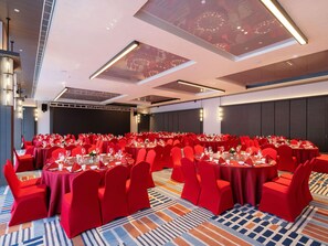 A large conference room with round tables, red chairs, and a patterned carpet. - Novotel Zibo New Hongcheng (Zibo)