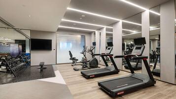 A modern gym with treadmills, weight machines, and a mirrored wall.