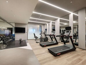 A modern gym with treadmills, weight machines, and a mirrored wall. - Novotel Zibo New Hongcheng (Zibo)
