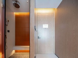 Un baño moderno con ducha, una puerta de madera y un cartel en la puerta.
