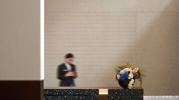 A reception desk with a vase of flowers and a blurred figure in the background.