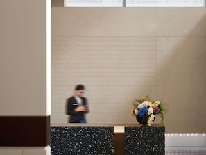 A reception desk with a vase of flowers and a blurred figure in the background.