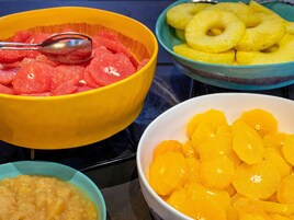 Una mesa con tazones que contienen frutas en rodajas.