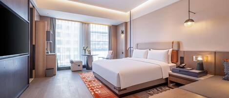 Una habitación de hotel moderna con una cama grande, mesitas de noche, un escritorio y un televisor.
