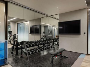 A gym with exercise equipment, a bench, and a television. - Novotel Zibo New Hongcheng (Zibo)