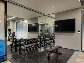 Un gimnasio con equipo de ejercicio, una banca y un televisor.