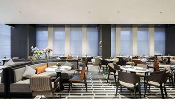 A modern dining area with sofas, chairs, and tables arranged for guests.