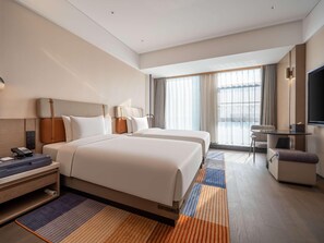 A hotel room with a large bed, bedside tables, a desk, a chair, a TV, and a window with curtains. - Novotel Zibo New Hongcheng (Zibo)