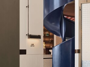 A modern interior with a 'Lobby Bar' sign, a metallic structure, and a speckled countertop.