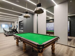 A pool table with a green felt surface, exercise equipment, and modern pendant lighting. - Novotel Zibo New Hongcheng (Zibo)