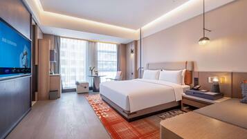 A modern hotel room with a large bed, bedside tables, a desk, and a TV.