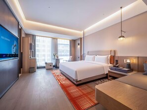 A modern hotel room with a large bed, bedside tables, a desk, and a TV. - Novotel Zibo New Hongcheng (Zibo)