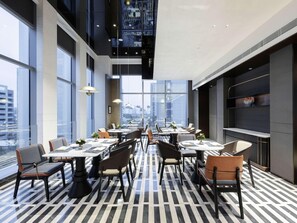 A modern dining area with high ceilings, large windows, and a patterned floor.