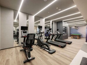 A gym with treadmills, elliptical machines, and a pool table.