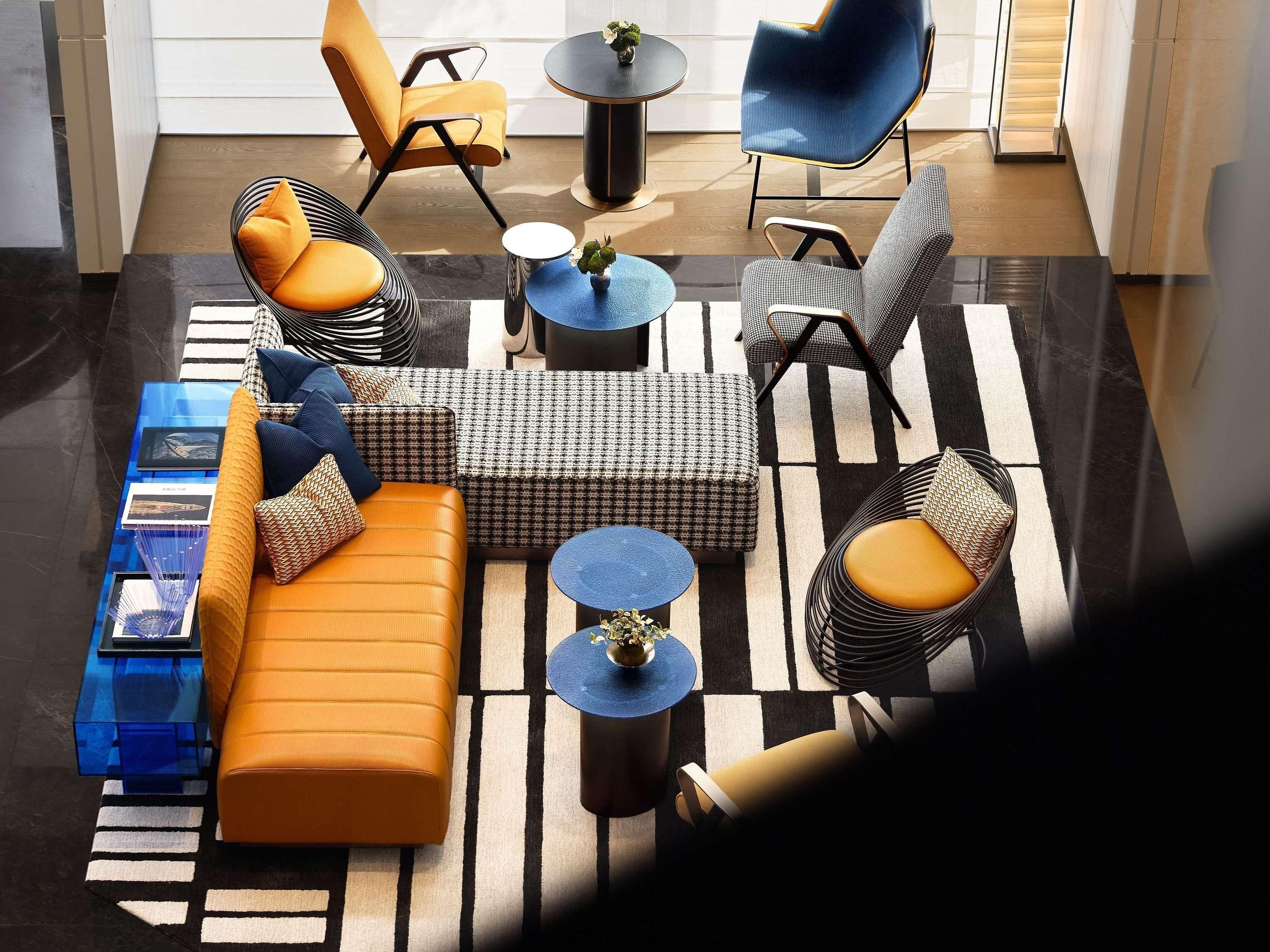 A modern living room with a sofa, chairs, a coffee table, and a patterned rug.