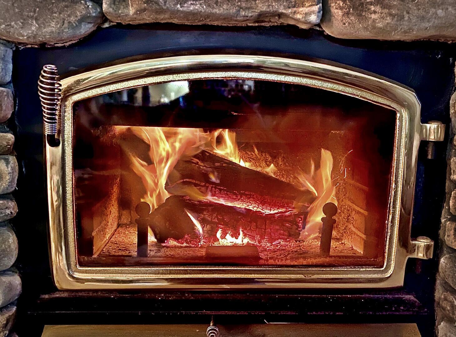 Une cheminée en pierre avec une porte en verre, à travers laquelle on peut voir le feu qui brûle à l’intérieur.