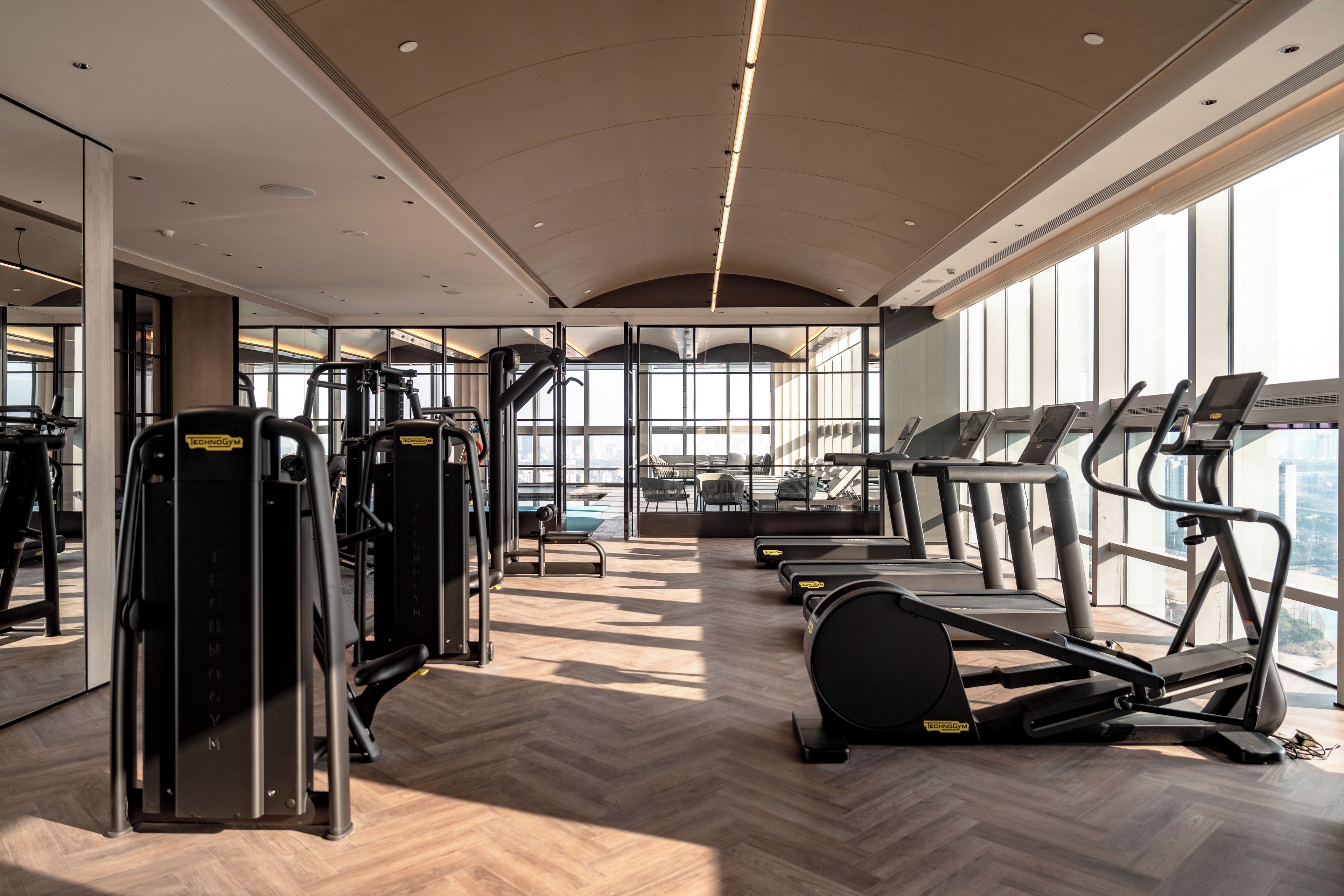 A gym with cardio machines, weight machines, and a herringbone-patterned floor.