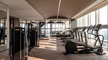 A gym with cardio machines, weight machines, and a herringbone-patterned floor.