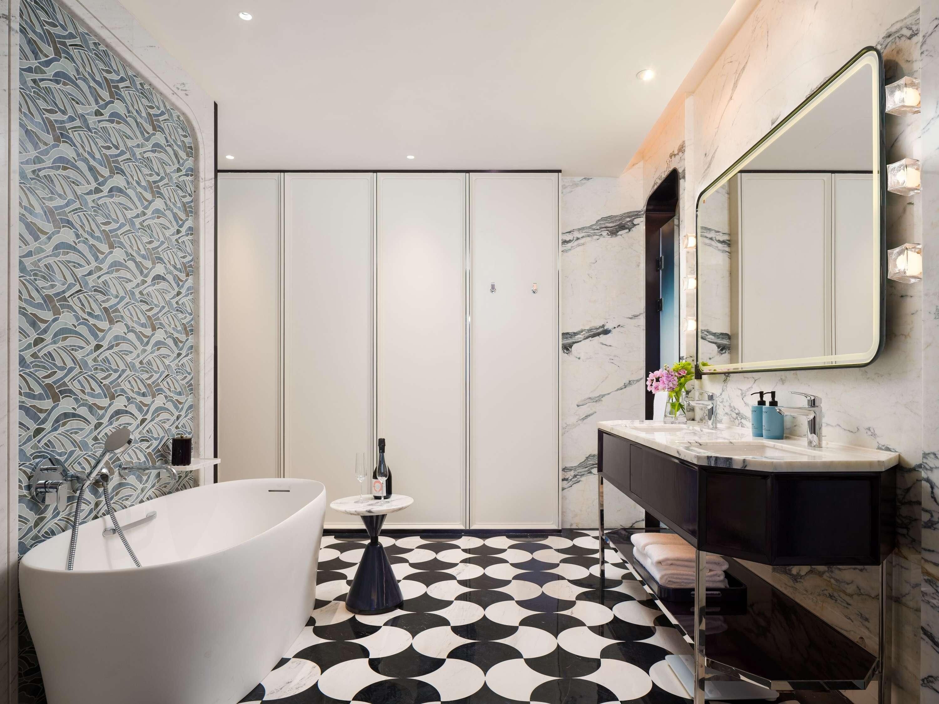 A modern bathroom with a freestanding bathtub, a vanity with a mirror, and a patterned floor.