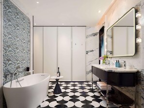 A modern bathroom with a freestanding bathtub, a vanity with a mirror, and a patterned floor. - Sofitel Changzhou Hi-tech District (Zhenjiang)
