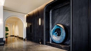 A modern hotel lobby with a marble floor, dark wood paneling, and a large abstract sculpture. - Sofitel Changzhou Hi-tech District (Zhenjiang)