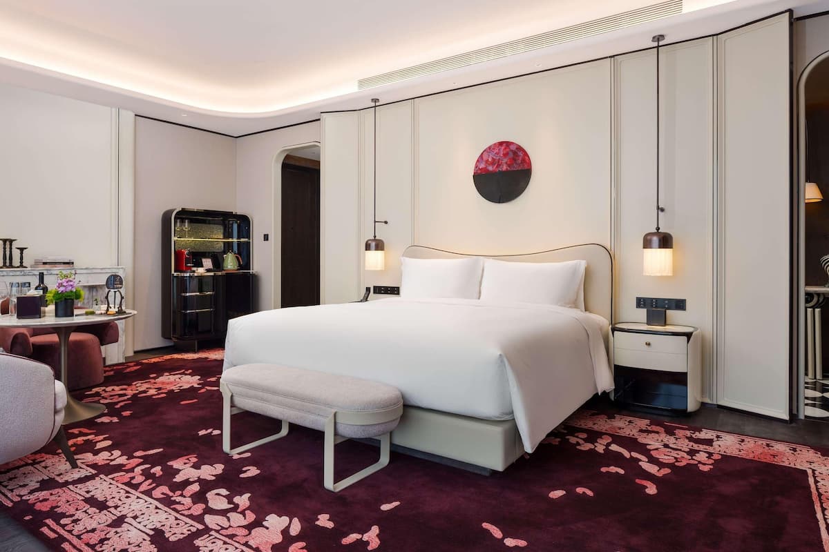Una habitación de hotel moderna con una cama grande, mesitas de noche, un escritorio y un armario.