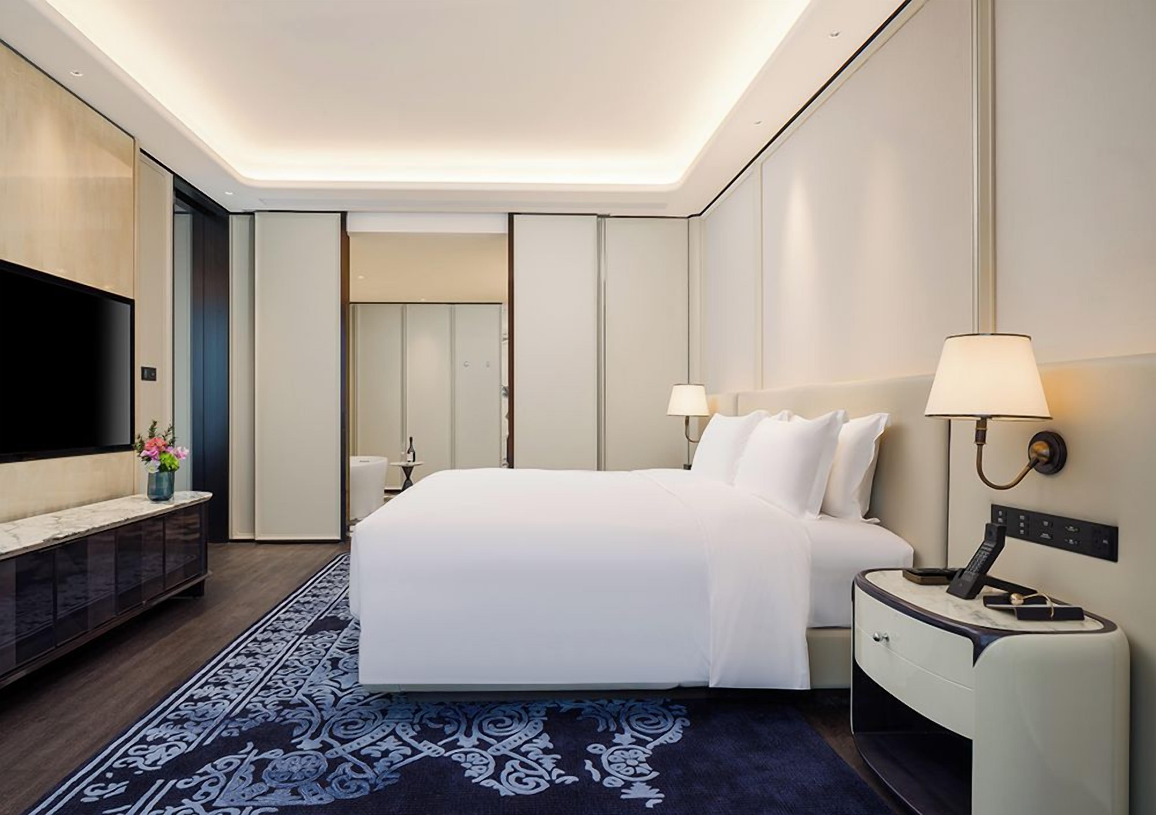 A hotel room with a large bed, bedside tables, a flat-screen TV, and a modern design.