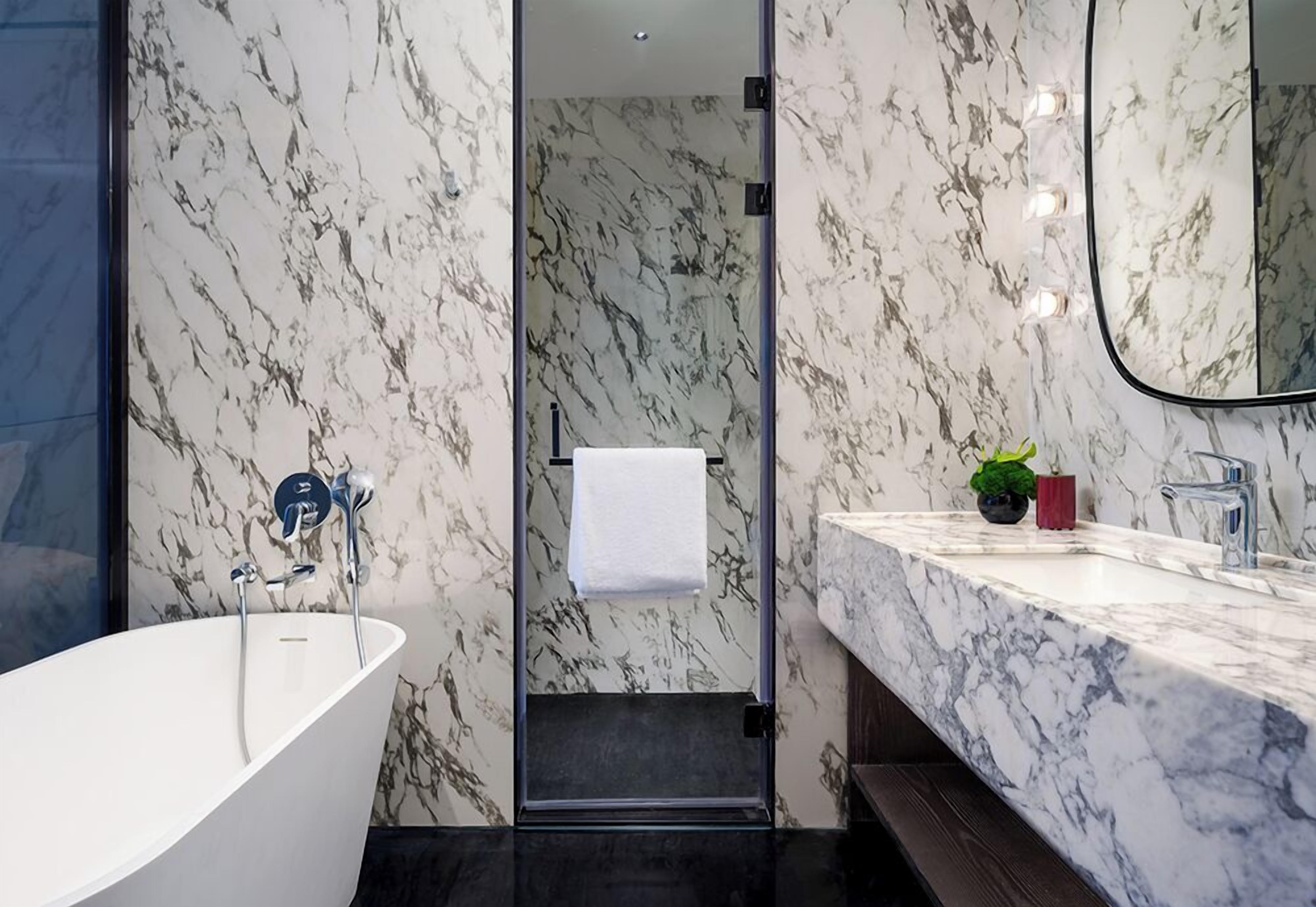 A modern bathroom with a freestanding bathtub, a sink with a marble countertop, and a mirror.