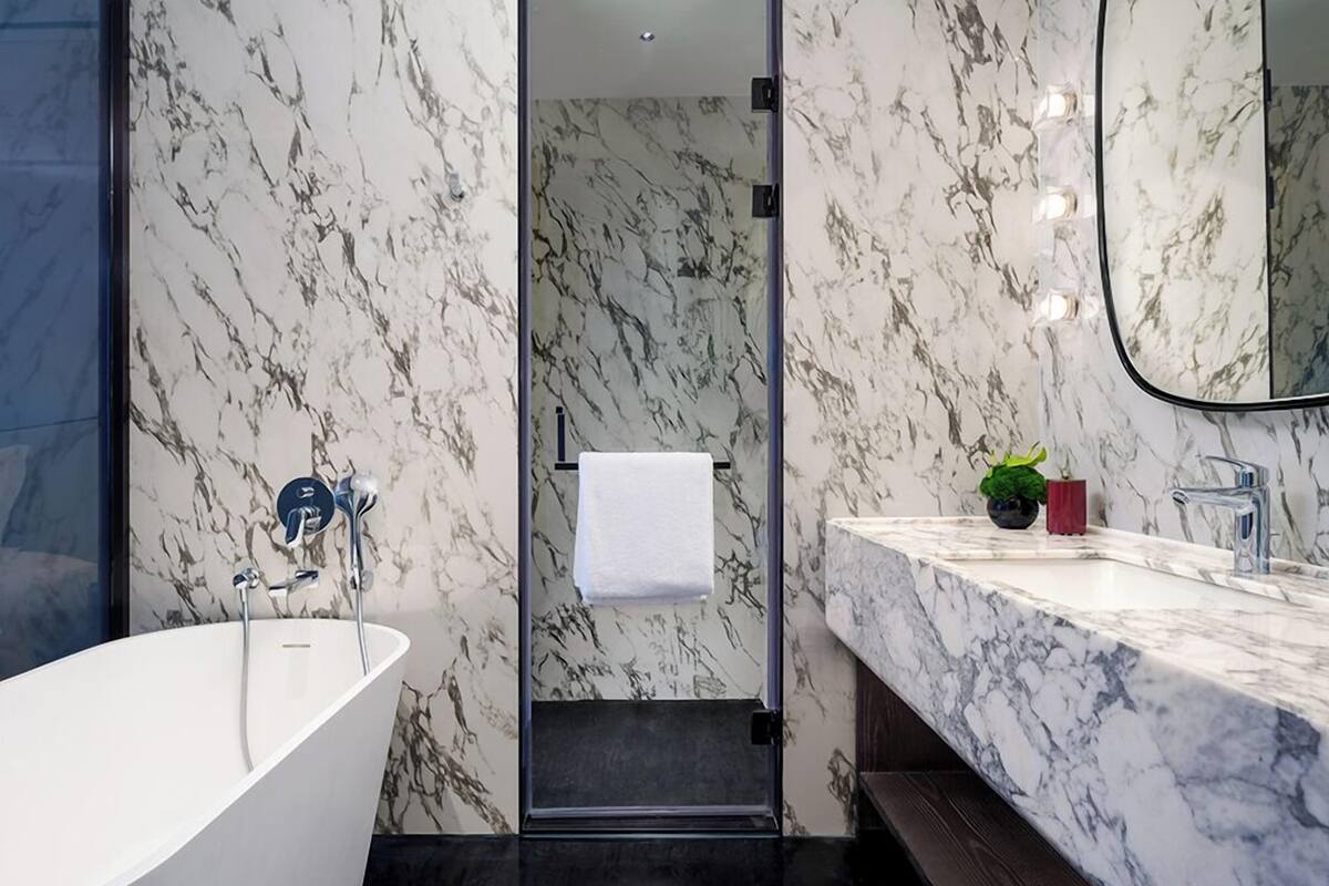 A modern bathroom with a freestanding bathtub, a sink with a marble countertop, and a mirror.
