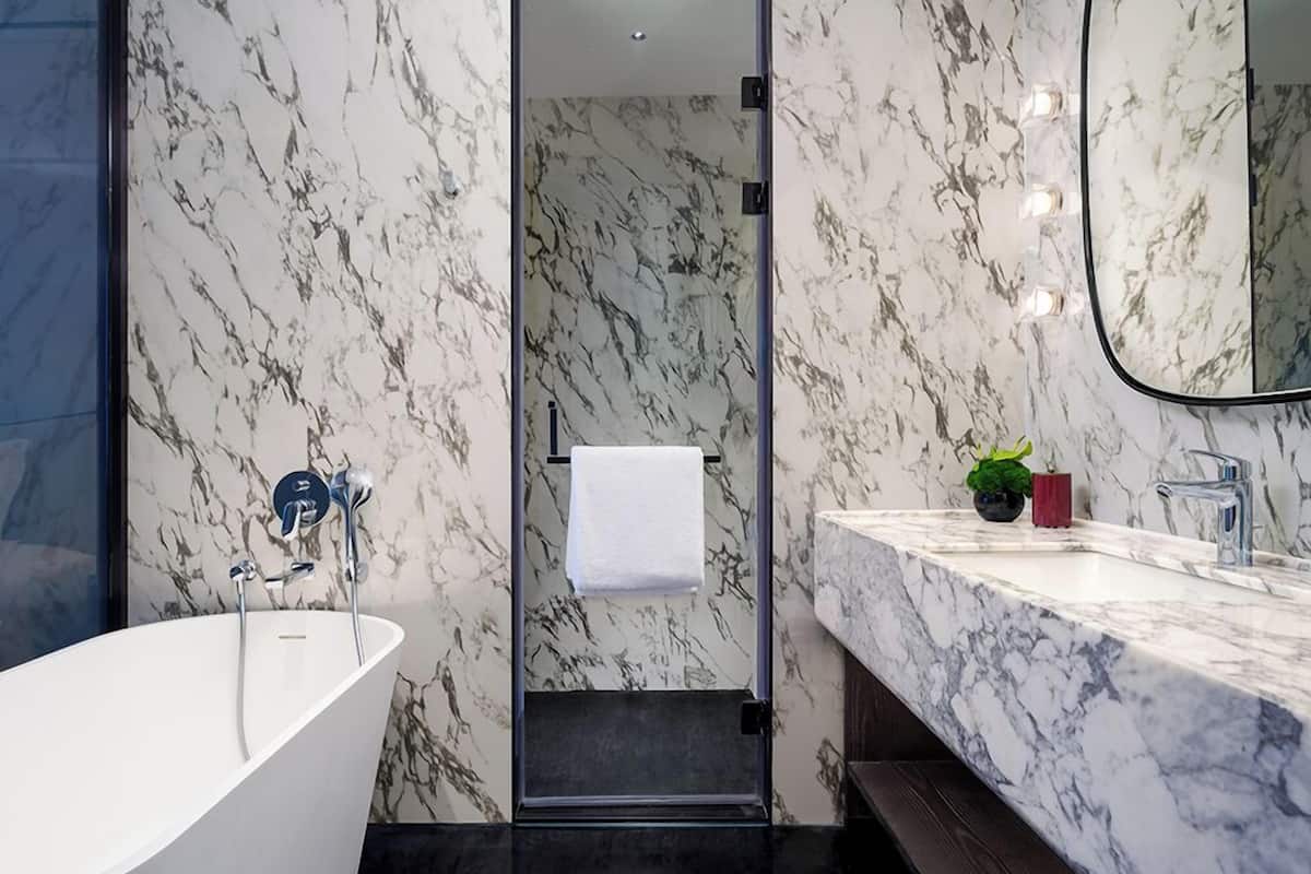 Un baño moderno con una bañera independiente, un lavamanos con encimera de mármol y un espejo.