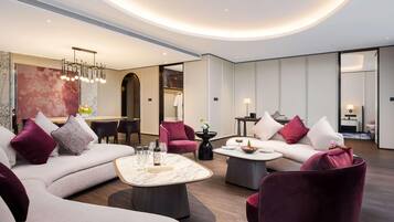 Un moderno vestíbulo de hotel con techo curvo, una zona de estar con sofás y sillones, una mesa de comedor y un gran cuadro abstracto.