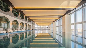 A long indoor swimming pool with a mirrored ceiling and seating area. - Sofitel Changzhou Hi-tech District (Zhenjiang)