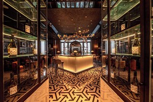 A bar area with a central counter, mirrored walls, and a patterned floor.