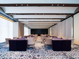 Un salón de conferencias con una larga mesa, sillas y una alfombra estampada.