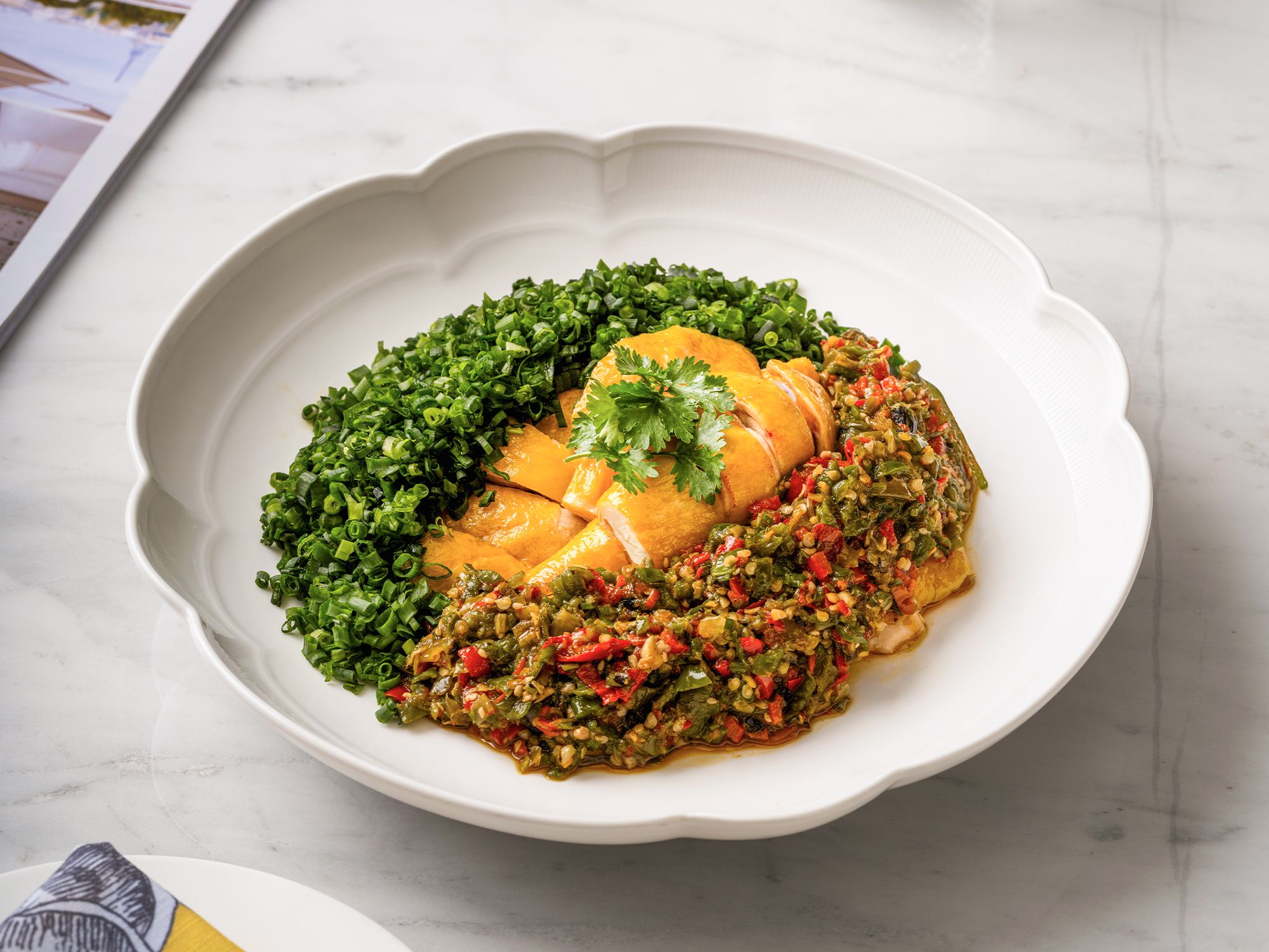 Un plato con un guiso de pollo, vegetales verdes y salsa, sobre un plato blanco.