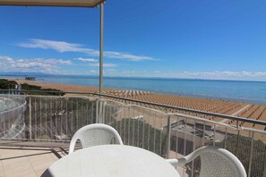 A balcony with a view of a beach and ocean. - Holiday apartment mit Balkon und Meerblick (Lignano Sabbiadoro)