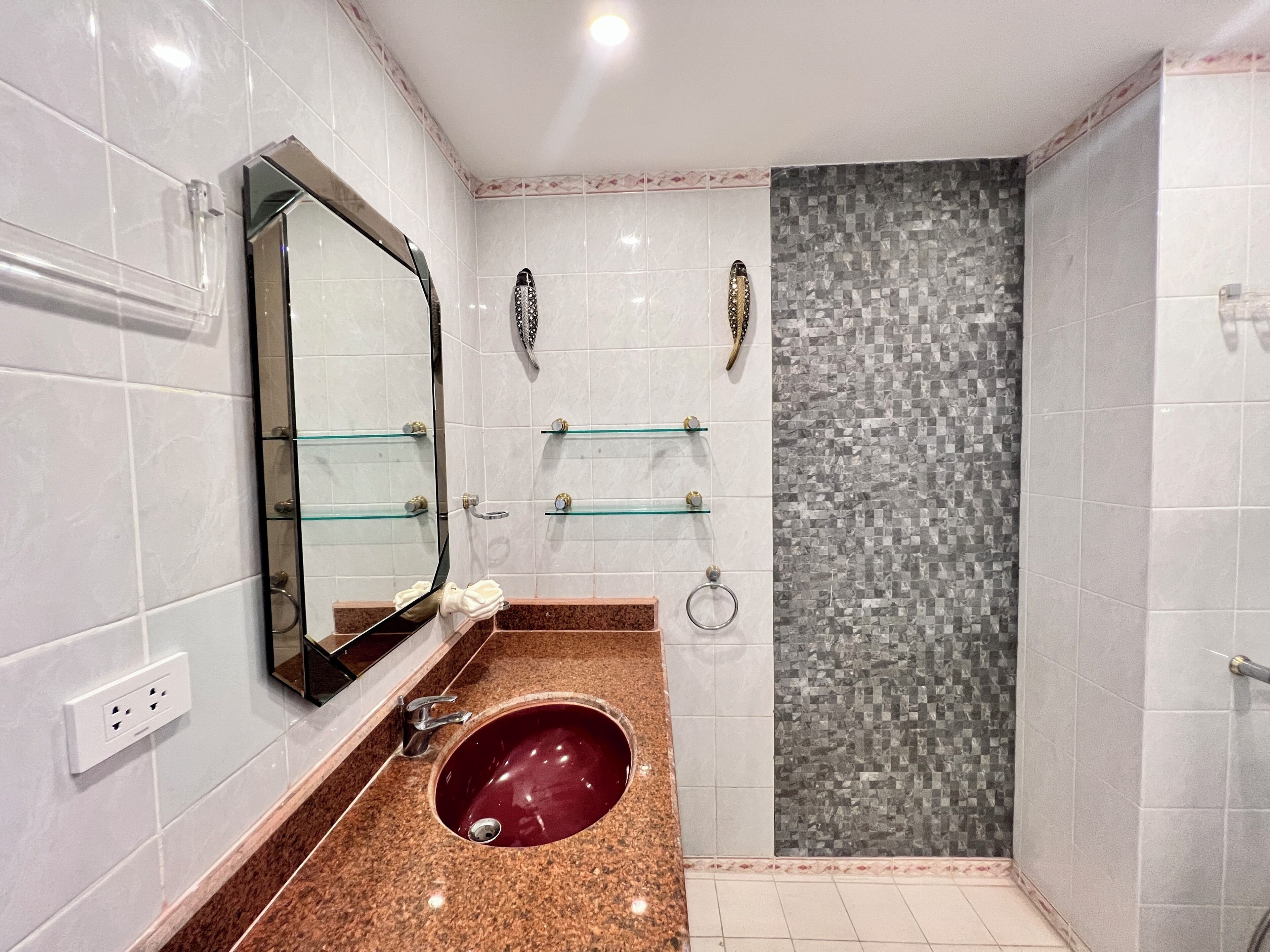 A bathroom with a marble sink, a glass shower enclosure, and a tiled shower wall.