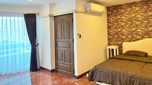 Un dormitorio con una cama, ventilador de techo, pared de piedra y aire acondicionado.