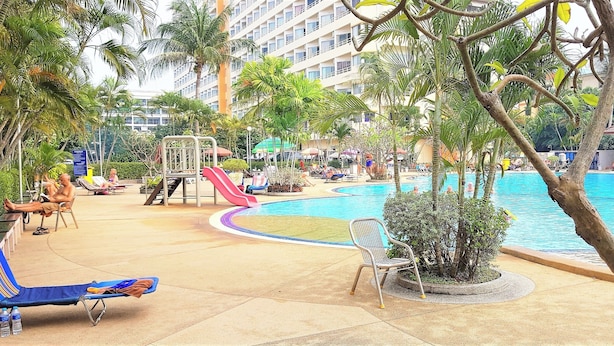 Un área de piscina con sillones reclinables, un tobogán y palmeras.