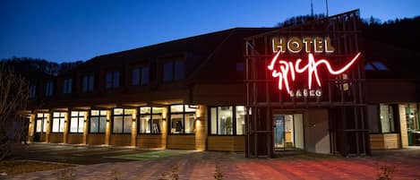A hotel with a prominent neon sign, a covered entrance, and a paved driveway.