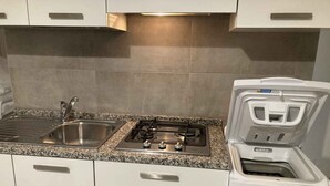 A kitchen with a stainless steel sink, a gas stove, and a built-in oven. - Holiday apartment mit Pool und Terrasse (Lignano Sabbiadoro)