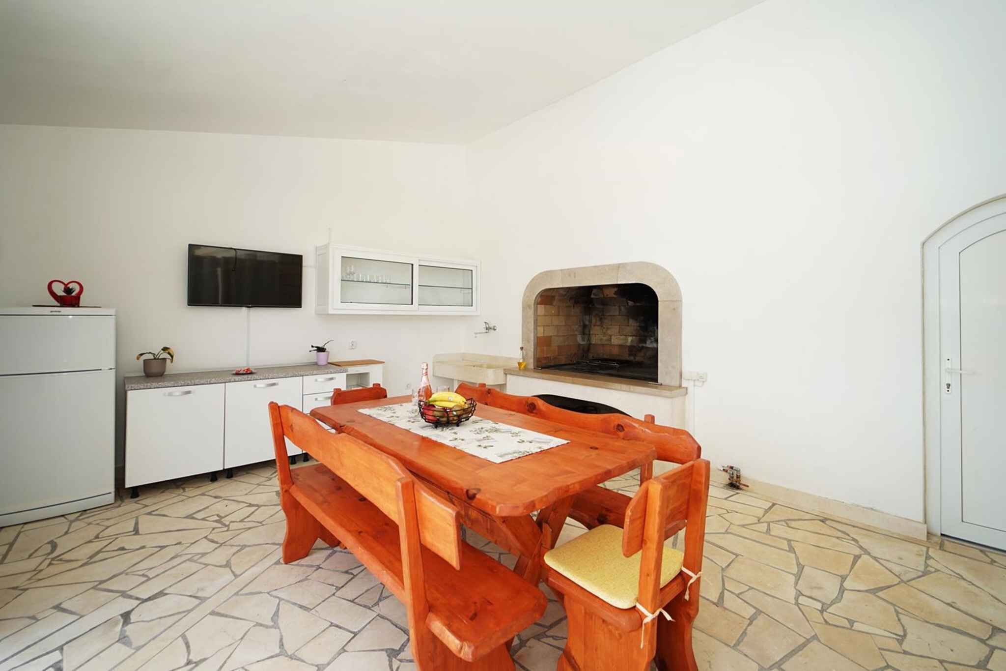 Una cocina compacta con armarios blancos, una mesa de comedor de madera y un horno empotrado.
