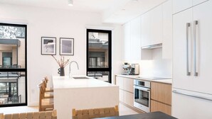 Een moderne keuken met een eiland, ingebouwde apparatuur en een eethoek met uitzicht.