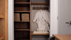 Ein begehbarer Kleiderschrank mit Holzböden, einem an einem Kleiderständer hängenden Bademantel und gewebten Körben.