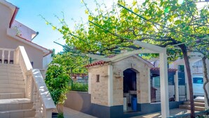 Een erf met een stenen gebouw, een trap en een pergola begroeid met klimplanten.