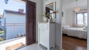 Ein Hotelzimmer mit Balkon, einem weißen Schminktisch, einem Bett und einer Pendelleuchte.